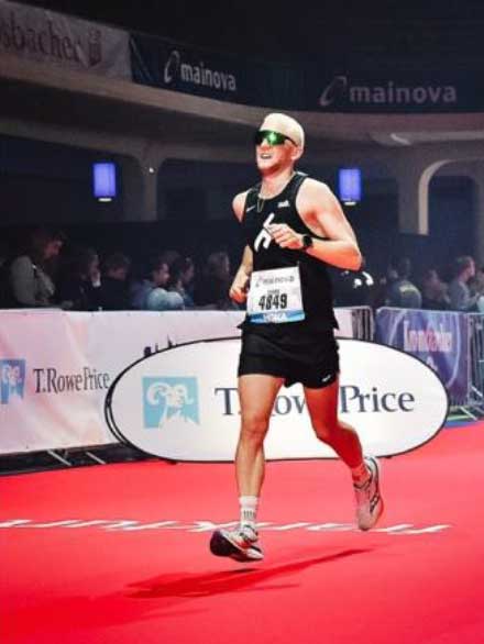 Sportler mit Startnummer läuft bei Indoor-Marathon über roten Teppich.